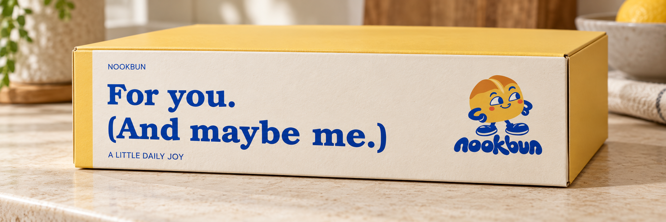 AI-generated visualization: Yellow Nookbun bakery box with a cream full-surface front and cobalt lettering.